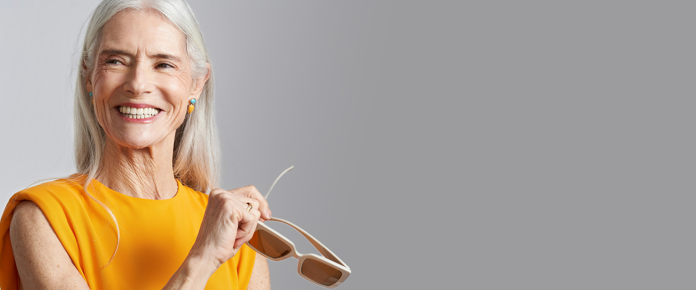 Smiling woman with silver hair in an orange top